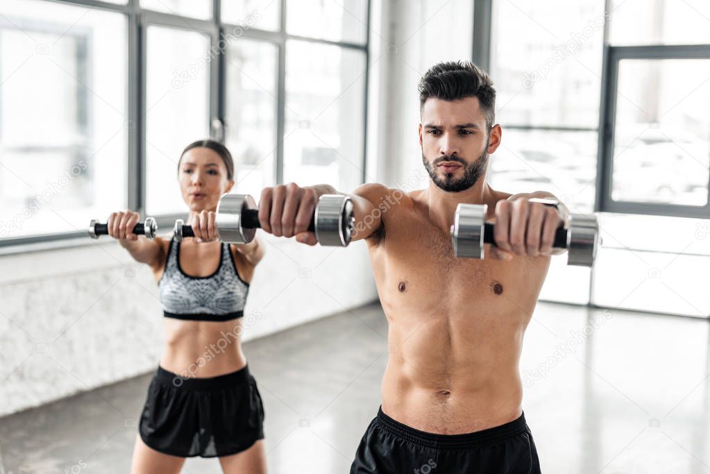 sporty young couple training with dumbbells in gym 