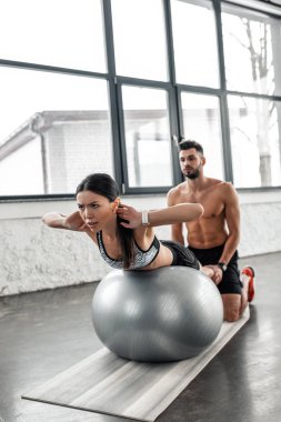 Genç sporcumuz üzerinde egzersiz yardımcı kas gömleksiz eğitmen top spor salonunda uyum.