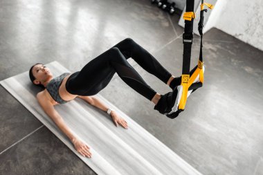 fitness kayışları üzerinde asılı ve spor salonunda yoga mat eğitimi sportif kızın yüksek açılı görünüş