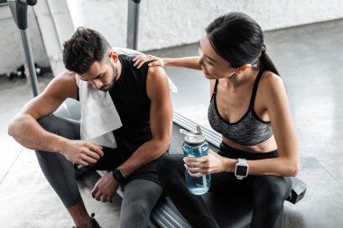 havlu ve şişe suyu birlikte spor salonunda treadmill dinlenme ile yorgun genç çiftin yüksek açılı görünüş