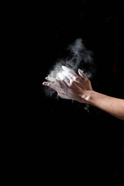 partial view of woman applying talcum powder on hands isolated on black clipart