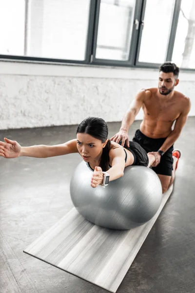 Shirtless Male Trainer Helping Sporty Girl Exercising Fitness Ball Gym — Stock Photo, Image