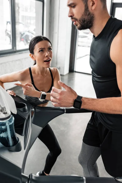 Aggressive Sportlerin Sieht Erschöpften Athletischen Mann Turnhalle Auf Laufband Laufen — Stockfoto