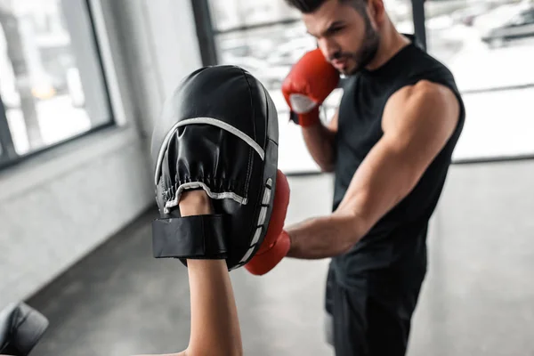 partial view of sportswoman and male boxer in boxing gloves training together in gym