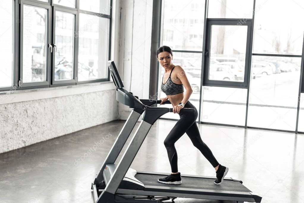 full length view of sporty young woman exercising on treadmill in gym