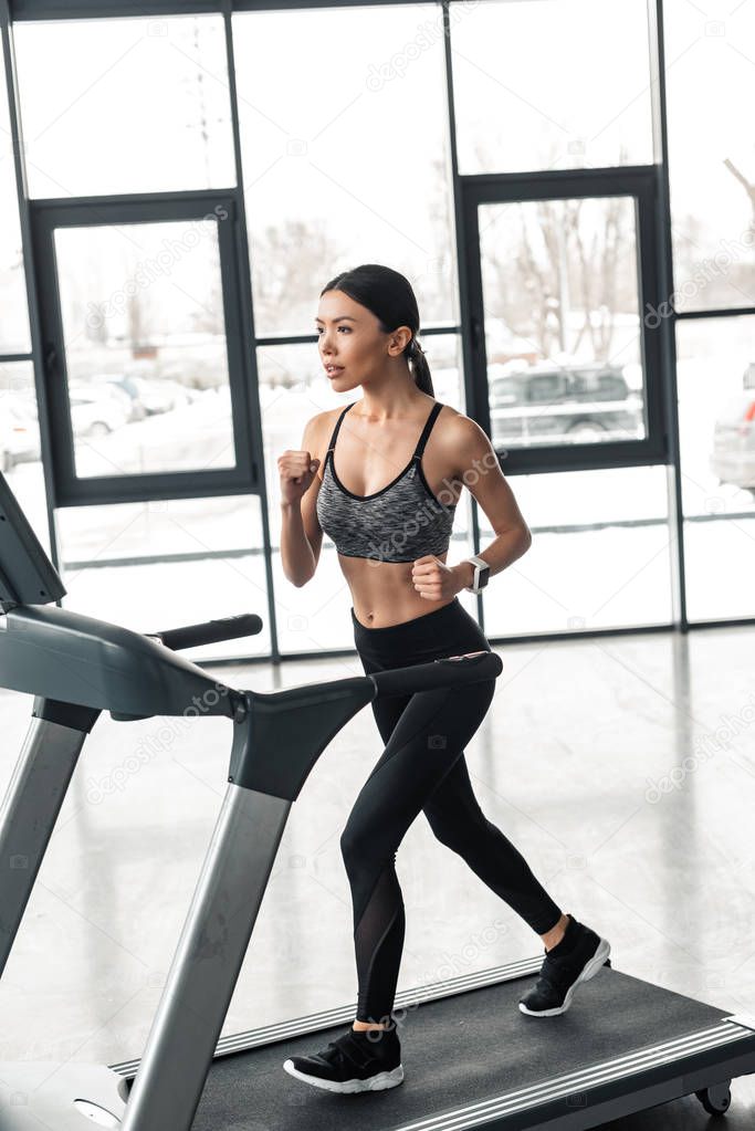 beautiful young sportswoman running on treadmill in gym 