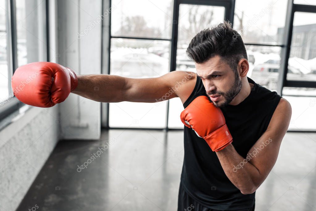 handsome sporty young man in boxing gloves training in gym 