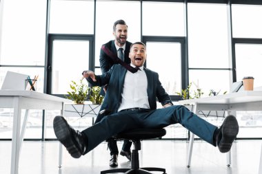 mutlu işadamı modern ofis sandalye heyecanlı iş arkadaşınız ile iterek 