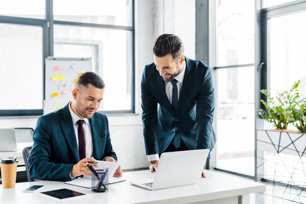 handsome businessman looking at coworker in modern office 