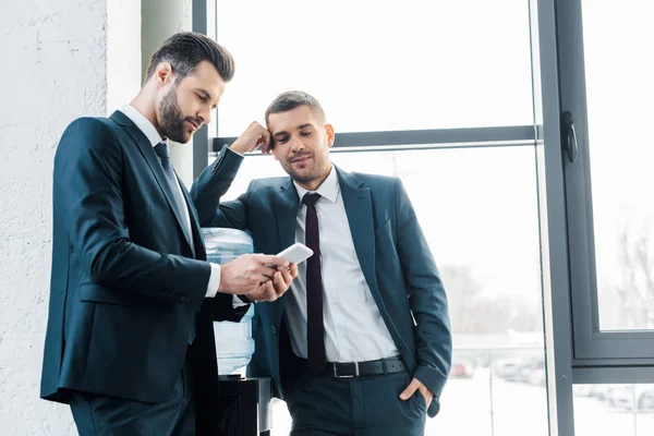 Hombre Negocios Guapo Mirando Teléfono Inteligente Cerca Colega Con Mano — Foto de Stock