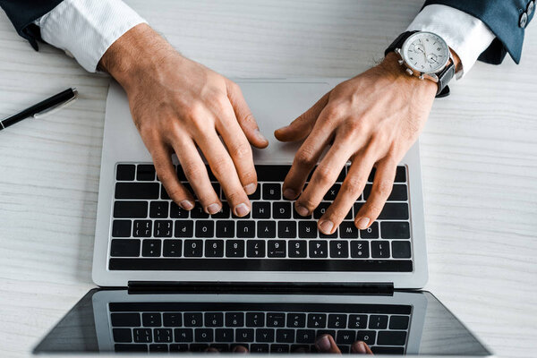 cropped view of man typing on laptop keyboard 