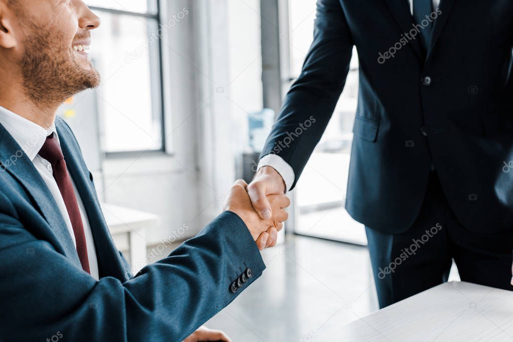 cropped viw of businessmen haking hands in modern office 