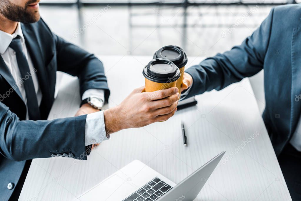 cropped view of businessmen toasting paper cups in modern office 