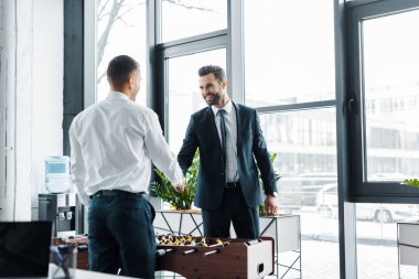 mutlu işadamları tokalaşırken langırt yakınındaki modern ofis 