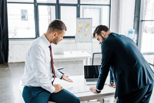 businessmen looking at document with diagram on desk in modern office 
