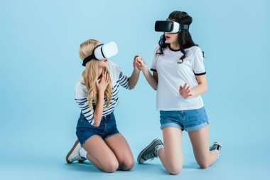 Korkmuş kız dizlerinin üzerinde duran ve üzerinde mavi arka plan elele Vr kulaklık