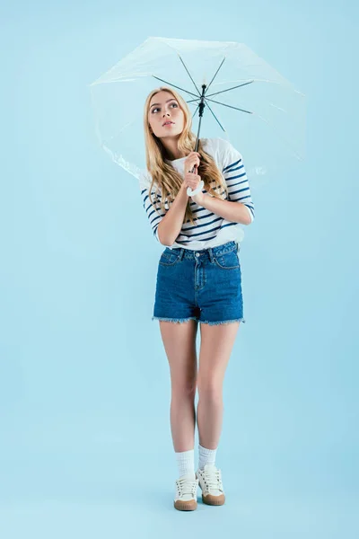 青の背景に傘を保持しているカジュアルな服装の女性 — ストック写真