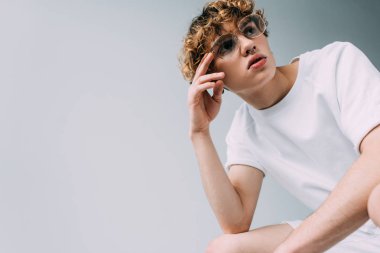 kıvırcık saçlı sittting gri izole gözlük ile ciddi adam