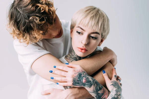 Man Curly Hair Embracing Blonde Woman Tattoos Isolated Grey — Stock Photo, Image