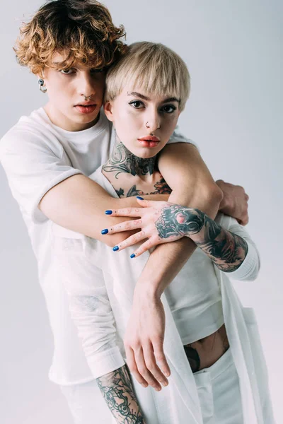 Άνθρωπος Σγουρά Μαλλιά Αγκαλιάζει Φίλη Τατουάζ Που Απομονώνονται Γκρι — Φωτογραφία Αρχείου