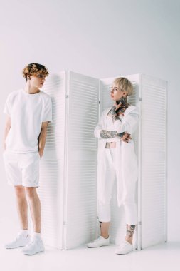 kıvırcık saçlı konumu ile olan yakışıklı adam cepler ve gri arka plan üzerine dövmeli kız arıyor eller