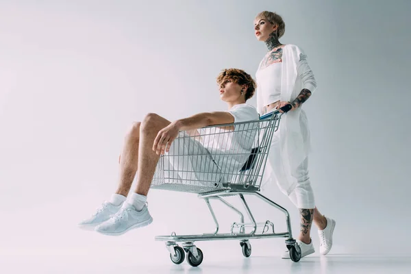 Attractive Woman Pushing Shopping Cart Handsome Boyfriend Isolated Grey — Stock Photo, Image