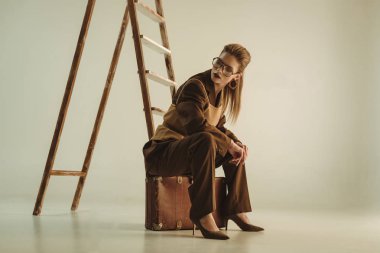 bej merdiveninde yakınındaki vintage çanta üzerinde oturan güzel şık kadın 