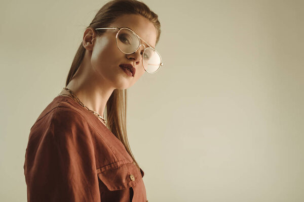 красивая стильная девушка позирует в модных очках изолированные на бежевый
