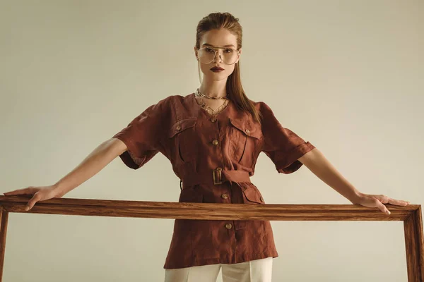 魅力的なモデルのベージュに分離された大きな木枠でポーズ — ストック写真