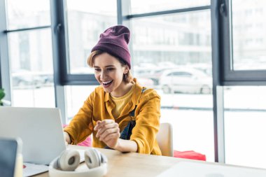 happy young female it specialist using laptop in loft office  clipart