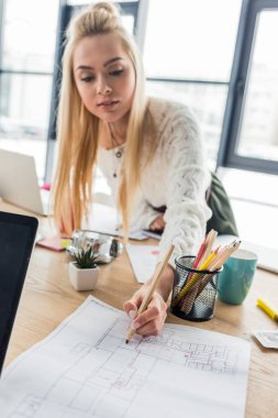 güzel kadın mimar loft ofis planı üzerinde çalışıyor