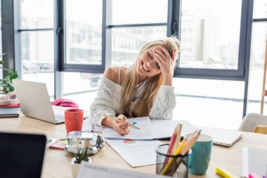 masada oturan ve loft Office grafikler üzerinde çalışma casual kadın iş kadını gülümseyen