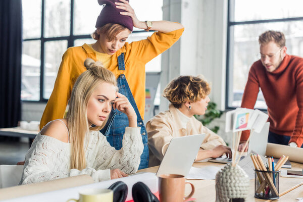 concentrated female and male casual businesspeople working on startup project with laptop in loft office