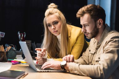 focused female and male it specialists using laptop in office clipart