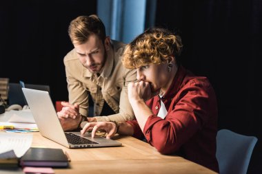 handsome confused male it specialists using laptop in office clipart