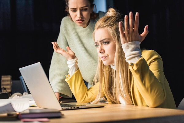 beautiful confused female it specialists using laptop in office