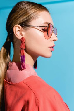 moda çekimi kadın giyim moda yaşam mercan ve üzerinde izole mavi poz güneş gözlüğü