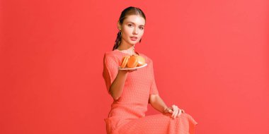 çekici kız yaşam mercan izole macaroons ile plaka tutarak. Yıl 2019 kavramının Pantone renk