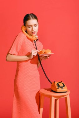 güzel bir kadınla macaroons ve yaşam mercan izole vintage döner telefon. Yıl 2019 kavramının Pantone renk