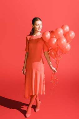 gülümseyen moda kız oturma ile poz mercan balonlar. Yıl 2019 kavramının Pantone renk