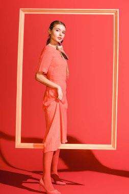 yaşam mercan üzerinde büyük çerçeve ile poz elbiseli güzel şık kız. Yıl 2019 kavramının Pantone renk