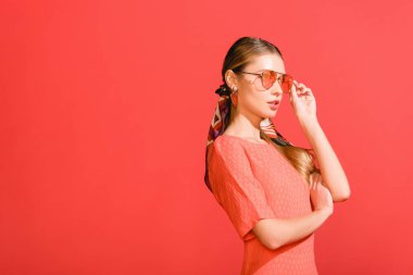 moda kız yaşayan poz mercan elbise ve izole kırmızı zemin üzerine güneş gözlüğü