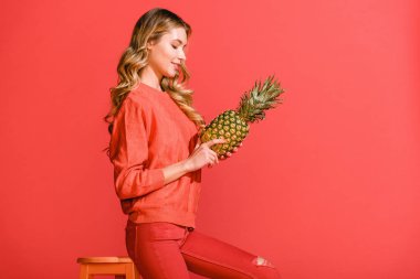 yaşam mercan izole dışkı, taze ananas tutan çekici gülümseyen kız 