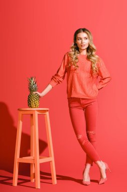 stylish beautiful woman holding fresh pineapple at stool on living coral  clipart