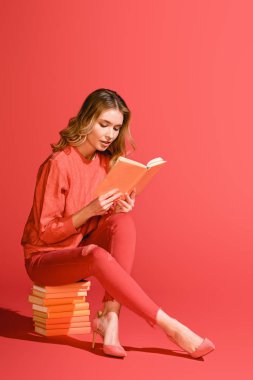 şık kız yaşam mercan kitap üzerinde otururken kitap okuma. Yıl 2019 kavramının Pantone renk