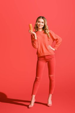 tatlı macaroons yaşam mercan üzerinde tutan neşeli kadın. Yıl 2019 kavramının Pantone renk