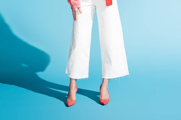 Обрезанный вид модной женщины, позирующей на голубом
