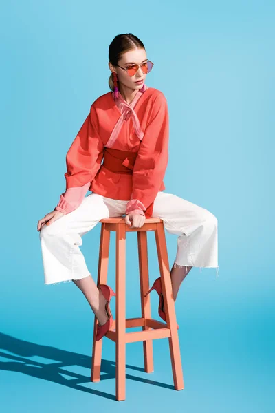 Модна Жінка Живому Кораловому Одязі Сонцезахисних Окулярах Позує Табуреті Синьому — стокове фото