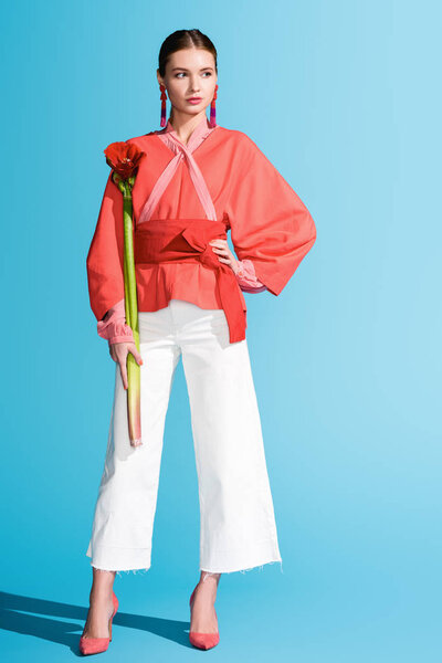 stylish elegant girl holding living coral flower on blue. Pantone color of the year 2019 concept