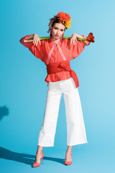 fashionable elegant girl in wreath holding living coral flower on blue. Pantone color of the year 2019 concept